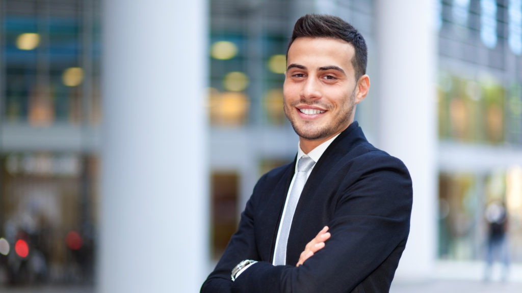 Independent Insurance Agency owner in a dark suit smiling at the camera with their arms crossed